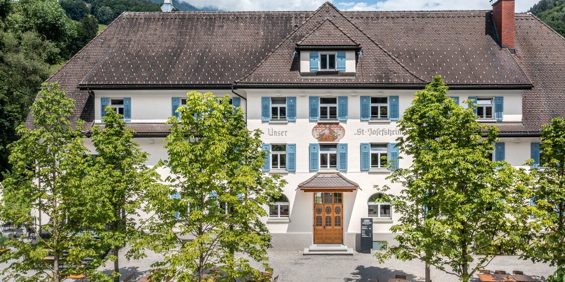 Das Josefsheim Restaurant & Hostel von Aussen mit Kastanienbümen und Terrasse im Vordergrund.  | © Silvretta Montafon - blateral