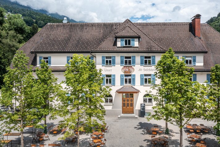 Das Josefsheim Restaurant & Hostel von Aussen mit Kastanienbümen und Terrasse im Vordergrund.  | © Silvretta Montafon - blateral