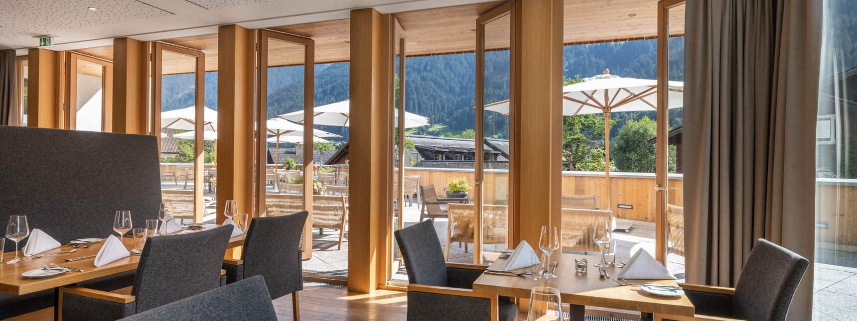 Innenraum vom Restaurant an der Fensterfront mit Blick auf die Terrasse des Sporthotel Silvretta Montafon in Gaschurn. | © Silvretta Montafon - blateral