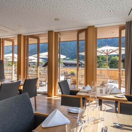 Innenraum vom Restaurant an der Fensterfront mit Blick auf die Terrasse des Sporthotel Silvretta Montafon in Gaschurn. | © Silvretta Montafon - blateral