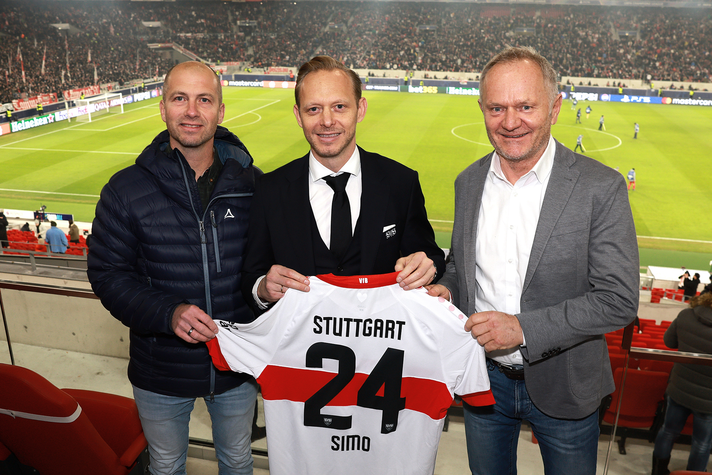 Drei Personen stehen im Fußballstadium bei der Übergabe eines Partnerschaftstrikots. | © Wolfgang List - www.perfectfotos.com