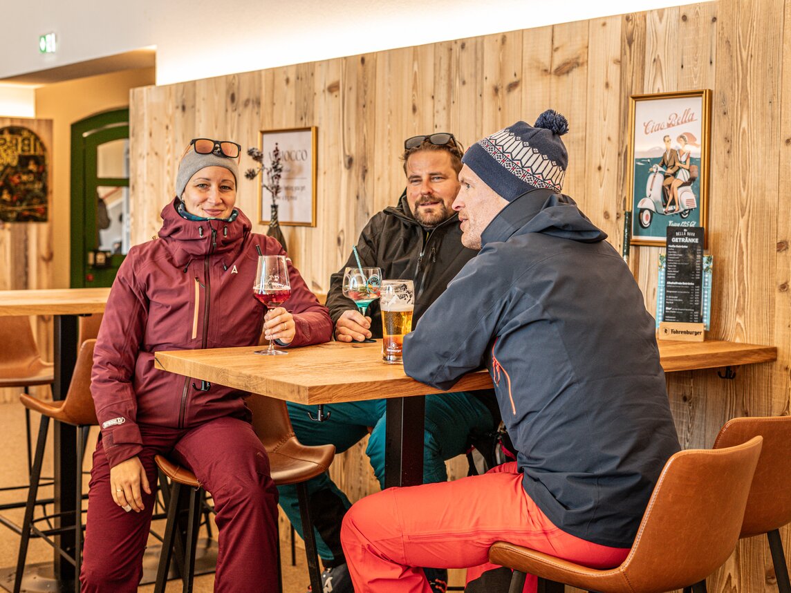 Drei Personen sitzen mit einem Getränk in der Bella Nova Bar. | © Silvretta Montafon - Vanessa Strauch