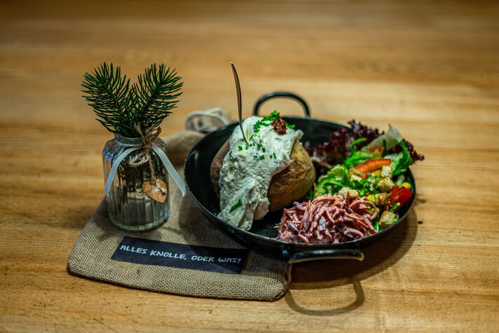 Eine Pfanne mit Pellkartoffel, Sauerrahm und Salat in der Grasjoch Hütte. | © Silvretta Montafon - Vanessa Strauch