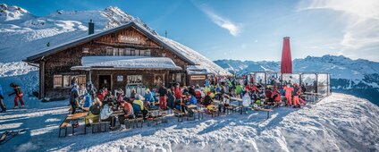 Die Grasjochhütte mit der gefüllten Terrasse bei schösten Winterwetter in der Silvretta Montafon. | © Silvretta Montafon - Marcel Mehrling