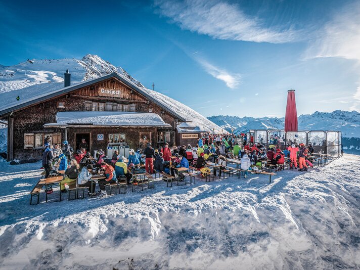 Die Grasjochhütte mit der gefüllten Terrasse bei schösten Winterwetter in der Silvretta Montafon. | © Silvretta Montafon - Marcel Mehrling
