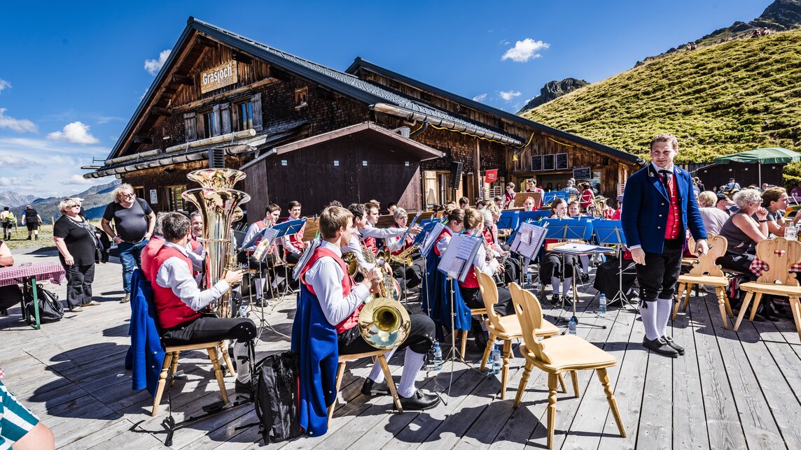 Blasmusikanten spielen auf der Terrasse beim Frühschoppen in der Grasjoch Hütte. | © Silvretta Montafon - Marcel Mehrling