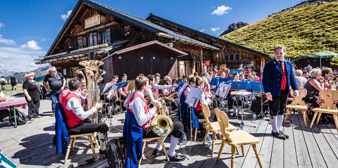 Blasmusikanten spielen auf der Terrasse beim Frühschoppen in der Grasjoch Hütte. | © Silvretta Montafon - Marcel Mehrling