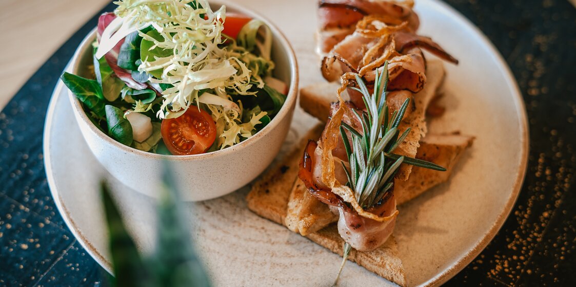 Hähnchenbrust und Speck auf Toastbrot, daneben ein gemischter Salat. | © Silvretta Montafon - Vanessa Strauch