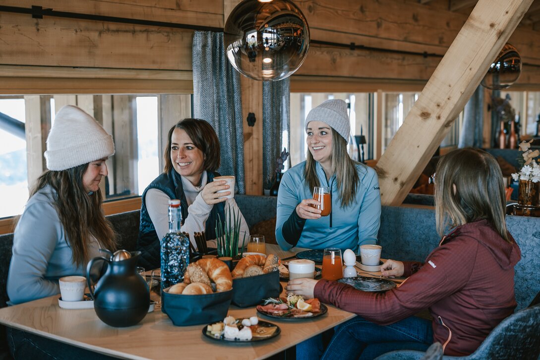 Vier Frauen sitzen an einem reichlich gedeckten Frühstückstisch. | © Silvretta Montafon - Vanessa Strauch