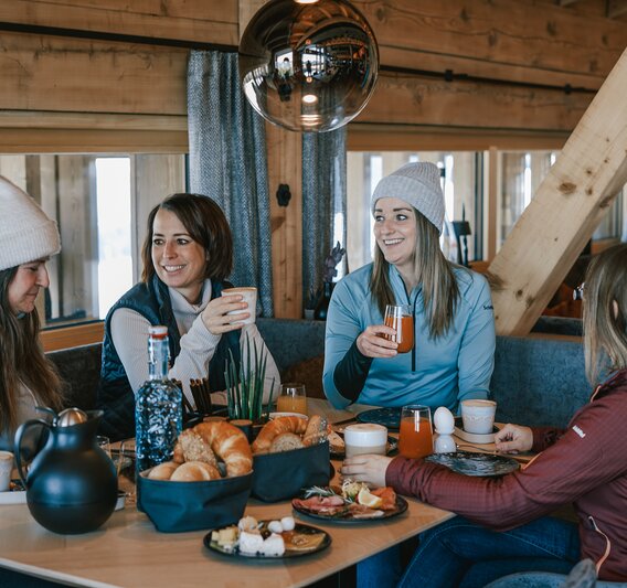 Vier Frauen sitzen an einem reichlich gedeckten Frühstückstisch. | © Silvretta Montafon - Vanessa Strauch