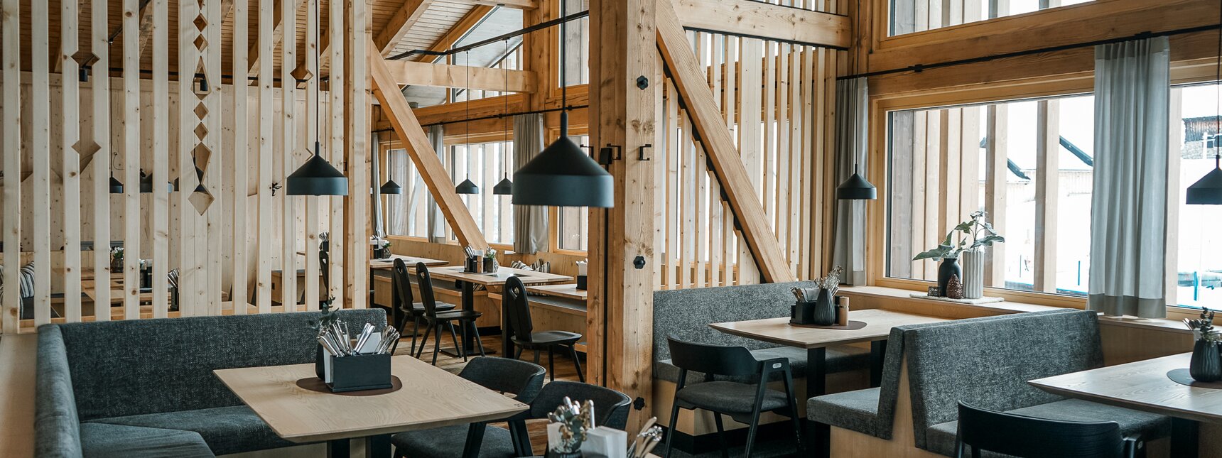 Modern gemütliches Bergrestaurant mit viel Holz und Grautönen und großen Fenstern. | © Silvretta Montafon - Vanessa Strauch
