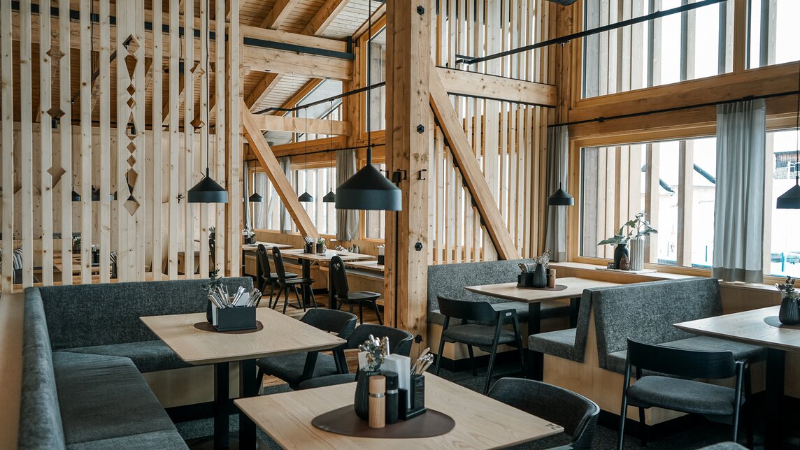 Modern gemütliches Bergrestaurant mit viel Holz und Grautönen und großen Fenstern. | © Silvretta Montafon - Vanessa Strauch