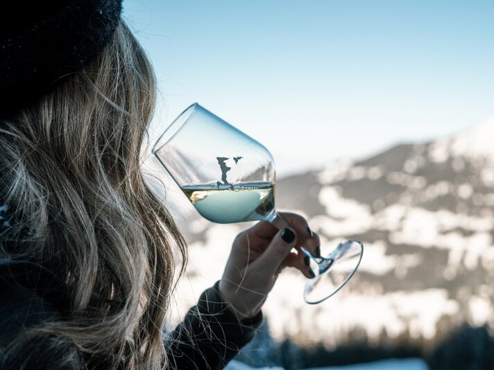 Eine Frau genießt ein Glas Weißwein auf der Terrasse des Kapellrestaurants. | © Silvretta Montafon - Vanessa Strauch