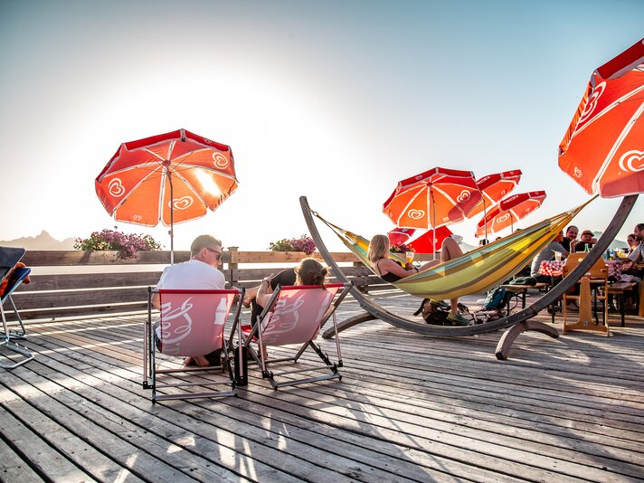 Die Terrasse mit Liegestühlen und Hängematten im Abendlicht bei untergehender Sonne. | © Silvretta Montafon - Friederike Weber