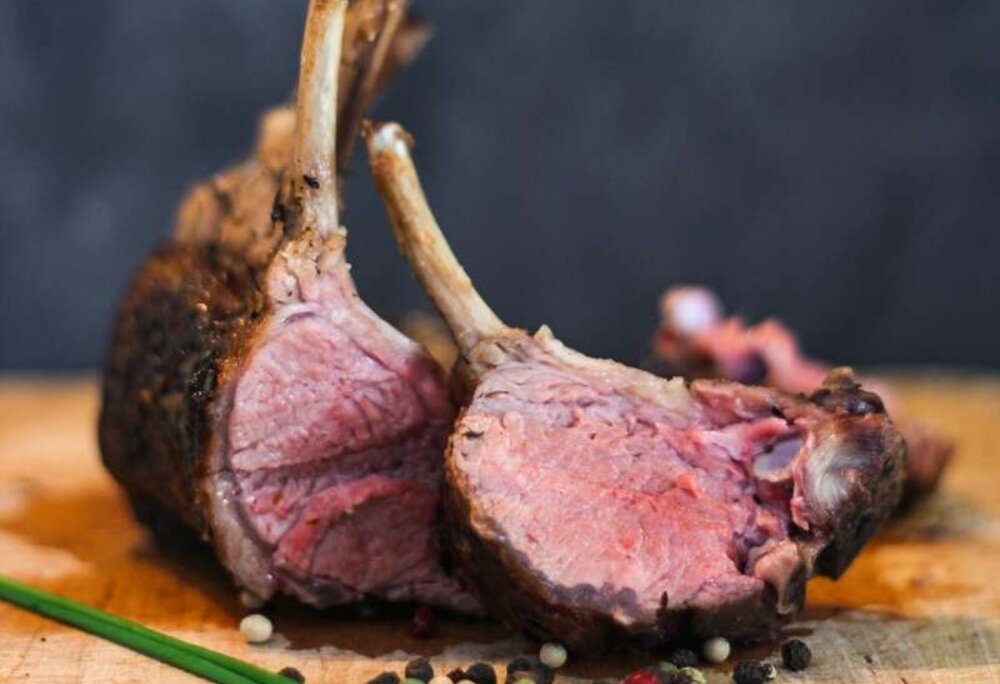Eine Keule vom Montafoner Steinschaf mit Pfefferkerner auf einem Holzbrett. | © Silvretta Montafon - Anna Wittwer