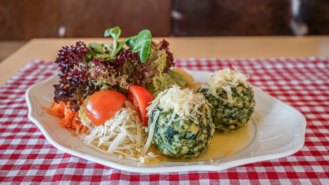 Ein Teller mit Spinatknödel auf der Terrasse des Rehsee Stöblis in der Silvretta Montafon. | ©  Silvretta Montafon - Vanessa Strauch