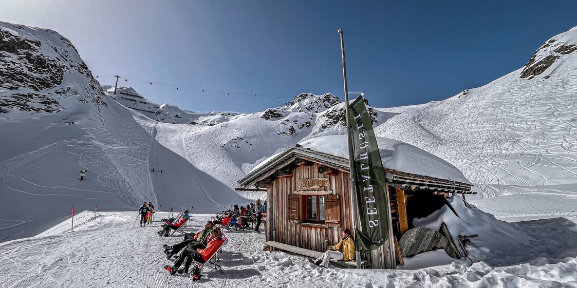 Eine Berghütte im Skigebiet mit Liegestühlen direkt an der Piste. | © Silvretta Montafon - Vanessa Strauch