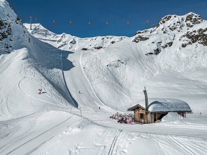 Eine Berghütte im Skigebiet mit Liegestühlen direkt an der Piste. | © Silvretta Montafon - Vanessa Strauch