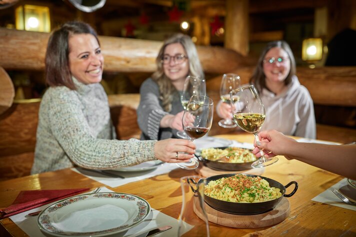  Drei Frauen stoßen mit Weinbei einer gemütlichen Spätzel-Party am Abend im Valisera Hüsli an. | © Silvretta Montafon - Stefan Kothner