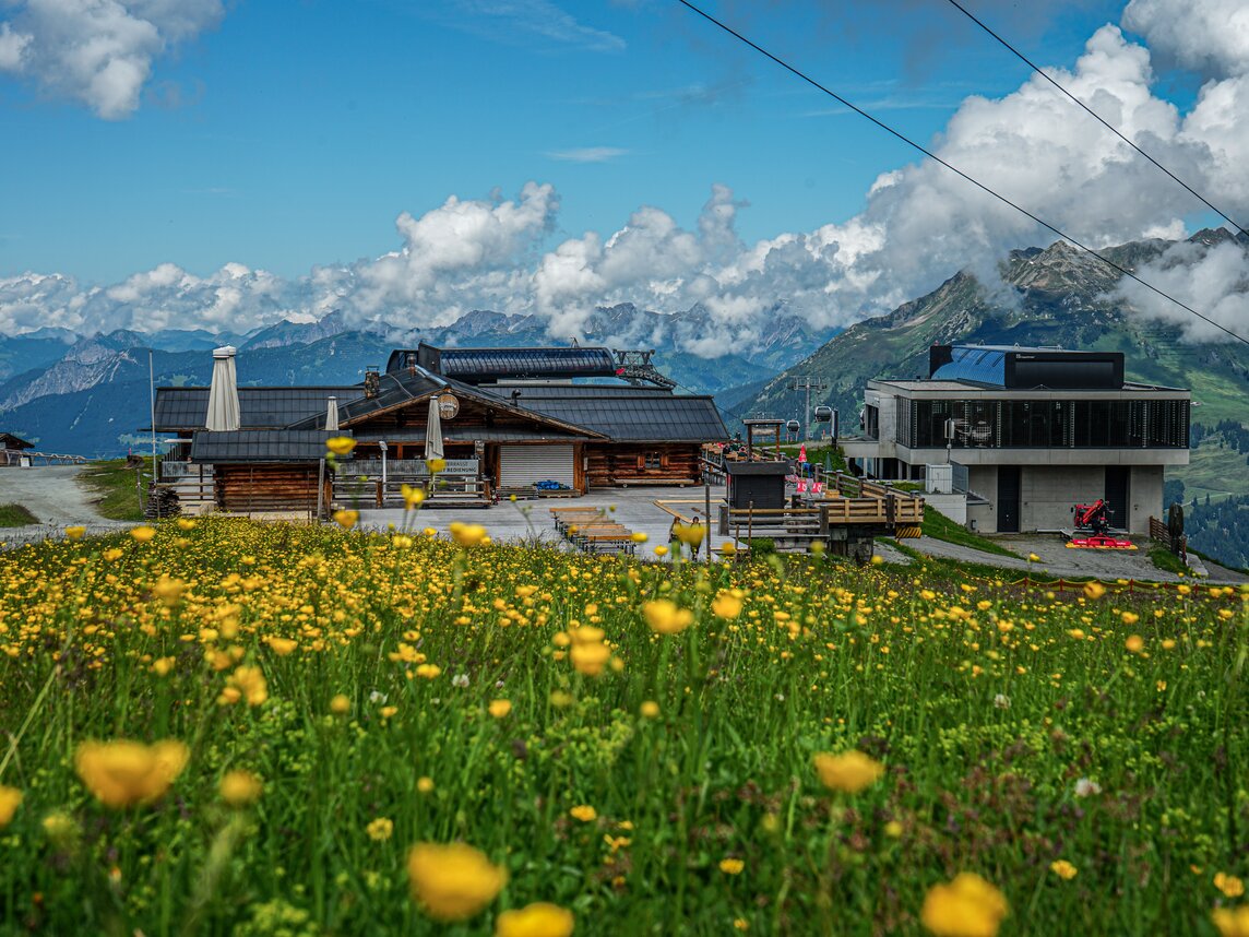Das Valisera Hüsli von vorne mit der Bergstation der Valisera Bahn im Hintergrund | © Silvretta Montafon - Vanessa Strauch