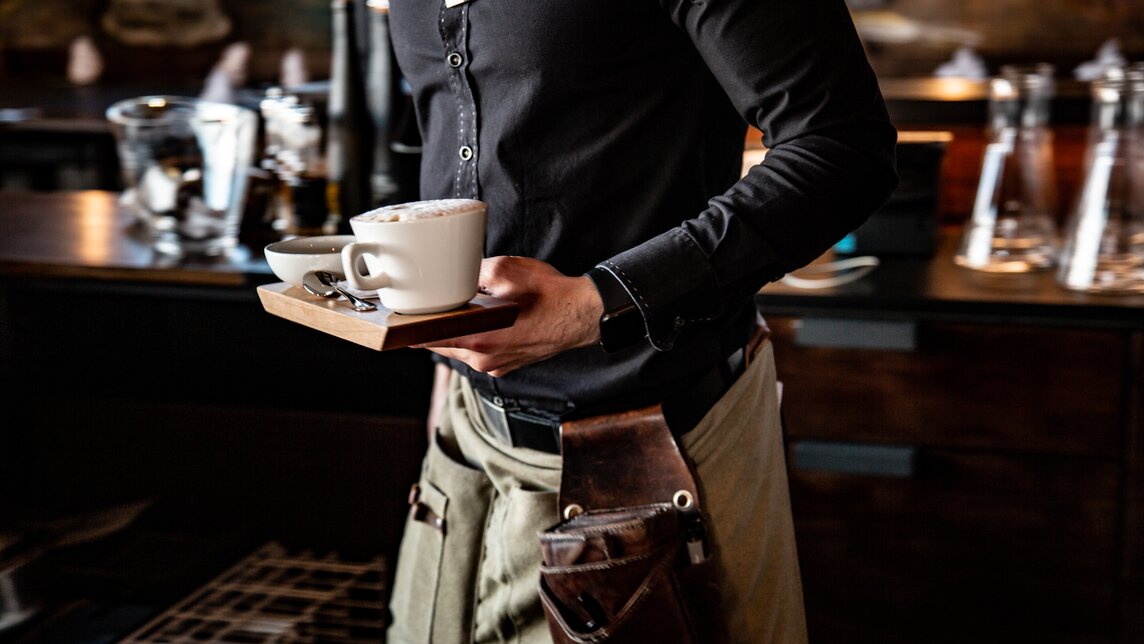 Ein Kellner bringt einen Kaffee in der Vinnova. | © Silvretta Montafon - Friederike Weber