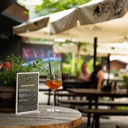Ein Glas Aperol auf einem Stehtisch auf der Terrasse der Alten Talstation. | © Silvretta Montafon