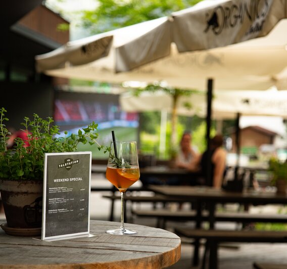 Ein Glas Aperol auf einem Stehtisch auf der Terrasse der Alten Talstation. | © Silvretta Montafon