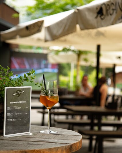 Ein Glas Aperol auf einem Stehtisch auf der Terrasse der Alten Talstation. | © Silvretta Montafon