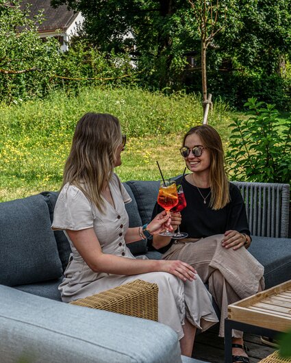 Gemütliche Sitzecke mit zwei Frauen und einem erfrischenden Getränk auf der Josefsheim Terrasse. | © Silvretta Montafon - Vanessa Strauch