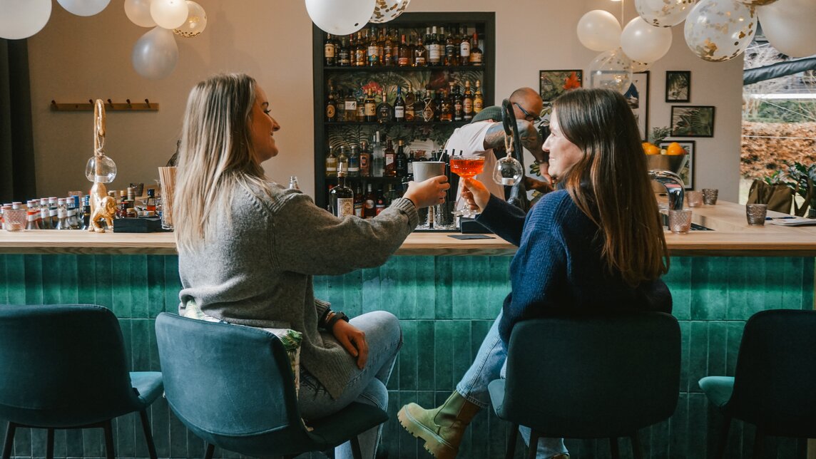 Zwei Frauen sitzen mit einem Drink an der Bar im Josefsheim Restaurant. | © Silvretta Montafon - Vanessa Strauch