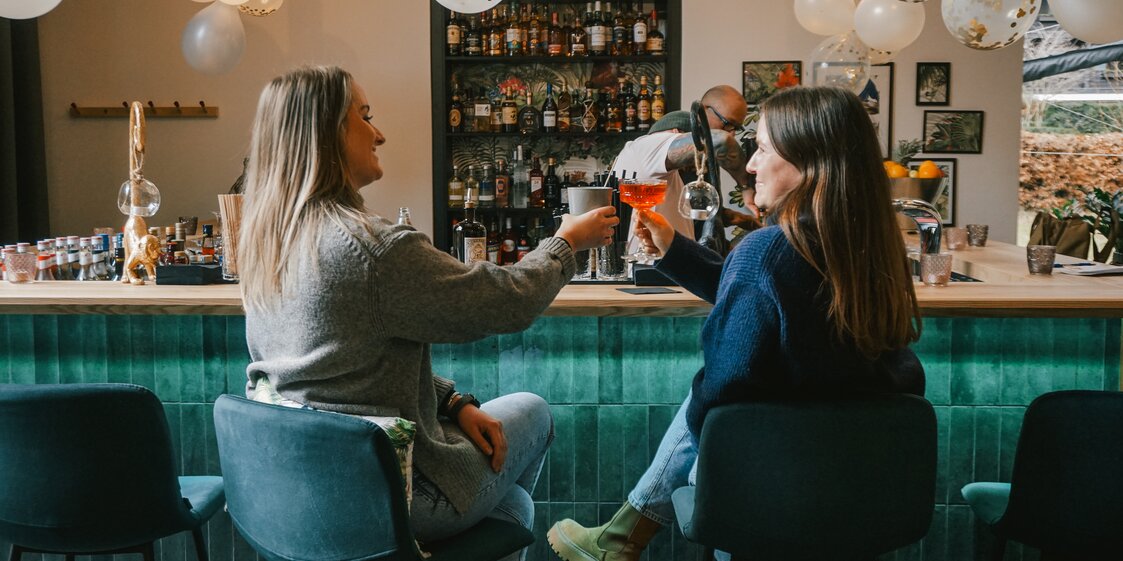 Zwei Frauen sitzen mit einem Drink an der Bar im Josefsheim Restaurant. | © Silvretta Montafon - Vanessa Strauch