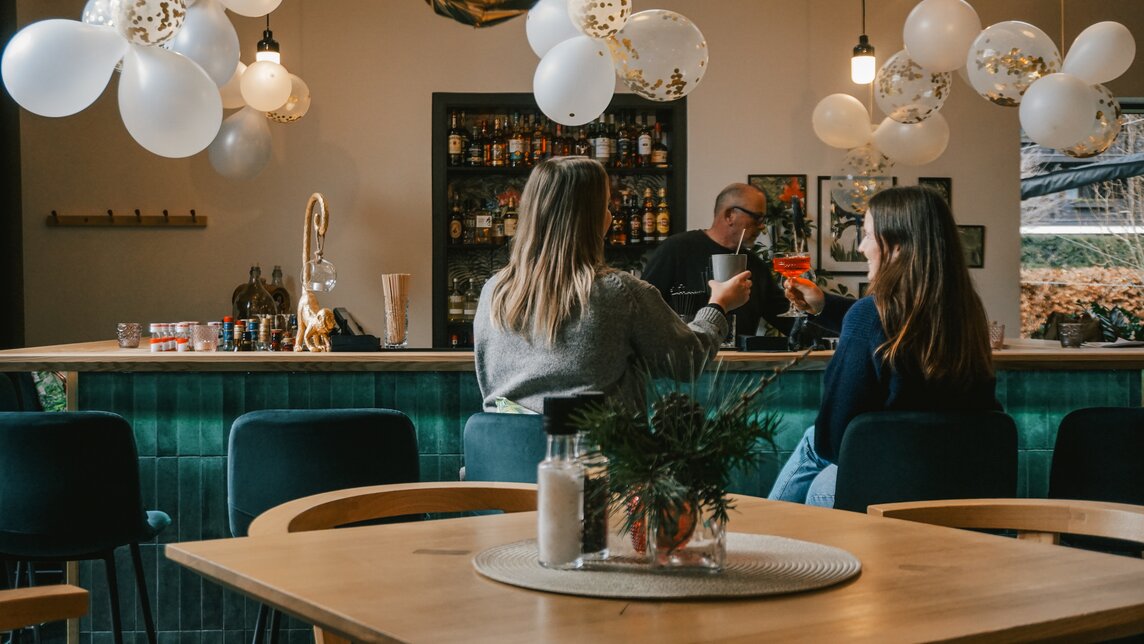 Zwei Frauen sitzen mit einem Drink an der Bar im Josefsheim Restaurant. | © Silvretta Montafon - Vanessa Strauch