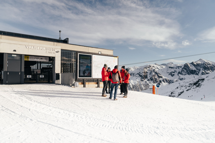 Eine Gruppe von Personen in roten Skijacken im Skiegebiet an der Valisera Bahn Bergstation. | © Montafon Tourismus - Marie Rudigier
