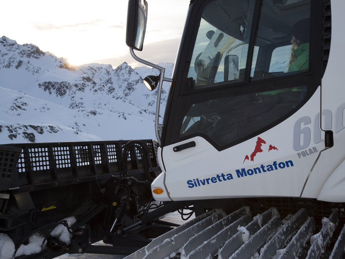 Eine Frau sitzt im Pistenbully bei untengehender Sonne im Skigebiet. | © Daniel Hug - Silvretta Montafon