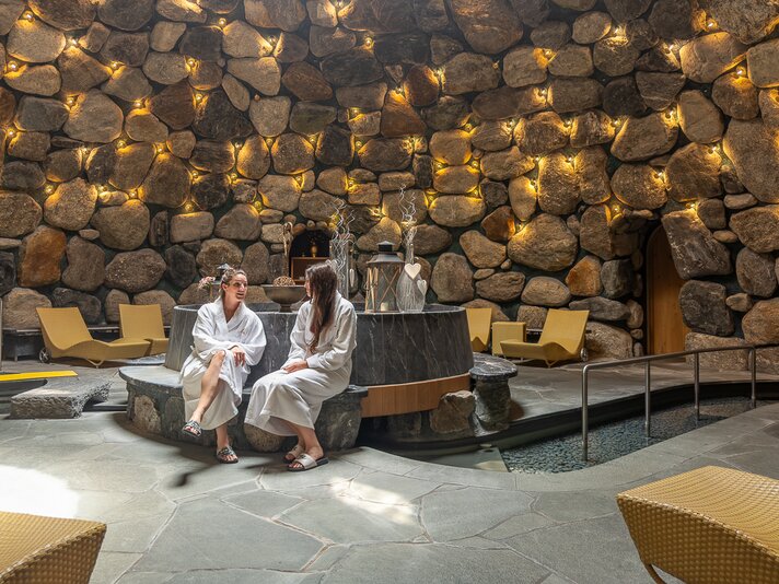 2 Personen sitzen in einem Spa bereich der aus einer Kuppel aus Steinen besteht | © Silvretta Montafon - Sara Kluber