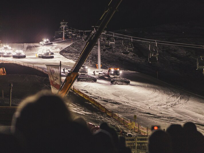 Einige Pistenbullys fahren bei Nacht in Formation eine Piste hinunter. | © Silvretta Montafon - Roadtyping