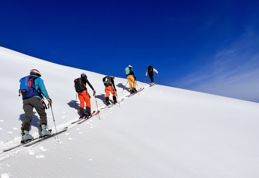Gruppe von Freeridern beim Aufstieg im Tiefschnee bei blauem Himmel. | © Silvretta Montafon - Vanessa Strauch