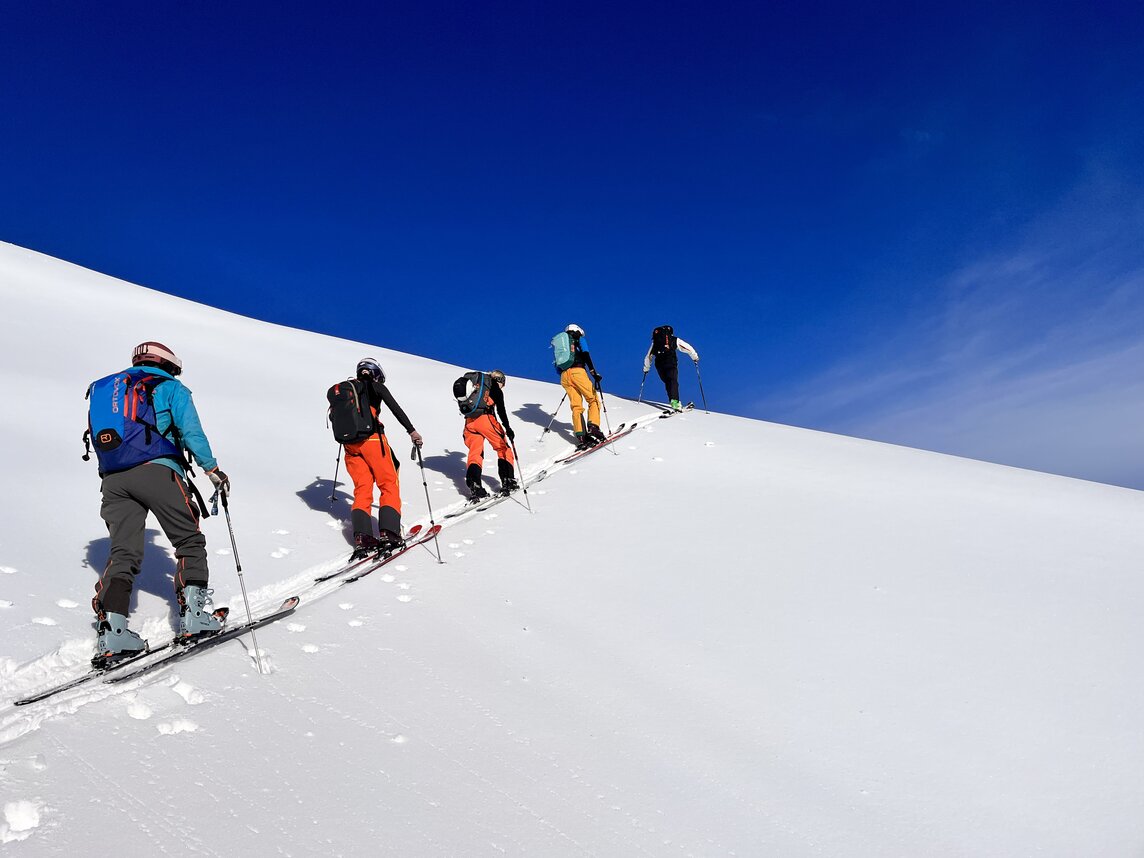 Gruppe von Freeridern beim Aufstieg im Tiefschnee bei blauem Himmel. | © Silvretta Montafon - Vanessa Strauch