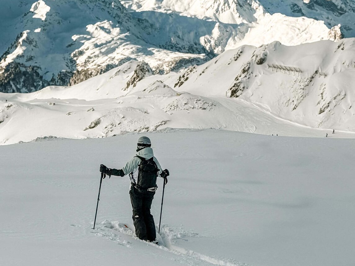 Eine Freeriderin steht kniehoch im Tiefschnee und genießt die Aussicht auf die Berge. | © Silvretta Montafon - Vanessa Strauch