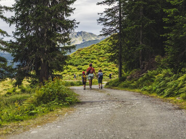 Eine Frau und zwei Kinder laufen auf einem Wanderweg in den Bergen. | © Silvretta Montafon - Roadtyping