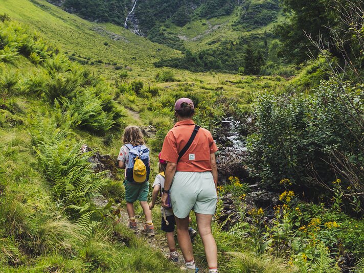 Eine Frau und zwei Kinder laufen auf einem Wanderweg in den Bergen. | © Silvretta Montafon - Roadtyping