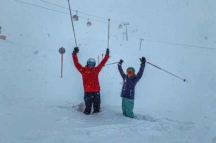 Zwei Personen stehen jubelnd im Tiefschnee im Skigebiet Silvretta Montafon. | © Silvretta Montafon