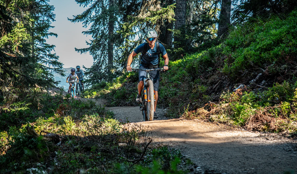 Ein Biker im Vordergrund und zwei Kinder im Hintergund fahren im Bikepark am Hochjoch in der Silvretta Montafon. | © Silvretta Montafon - Friederike Weber