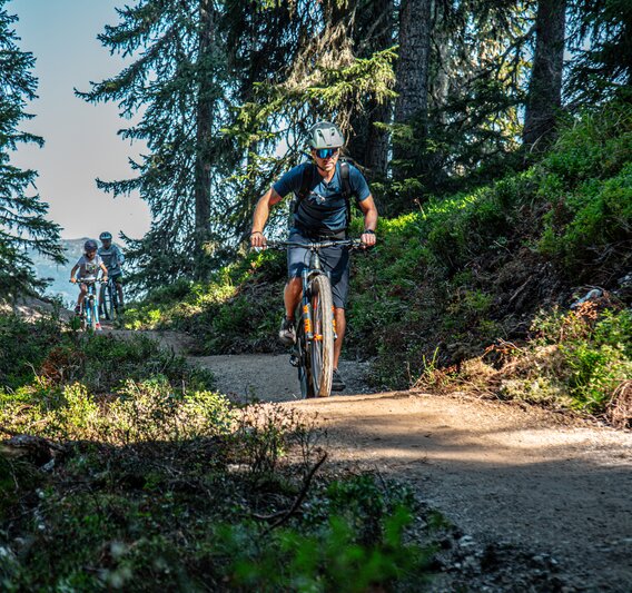 Ein Biker im Vordergrund und zwei Kinder im Hintergund fahren im Bikepark am Hochjoch in der Silvretta Montafon. | © Silvretta Montafon - Friederike Weber