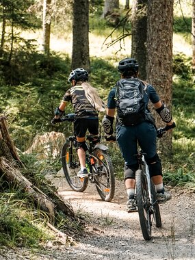 Eine Frau und ein Mädchen fahren auf einem Biketrail im Wald am Hochjoch in der Silvretta Montafon. | © Silvretta Montafon - Vanessa Strauch