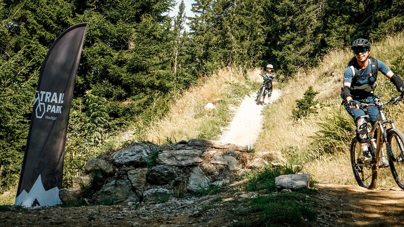 Eine Frau und ein Mädchen fahren auf einem Biketrail im Wald am Hochjoch in der Silvretta Montafon. | © Silvretta Montafon - Vanessa Strauch