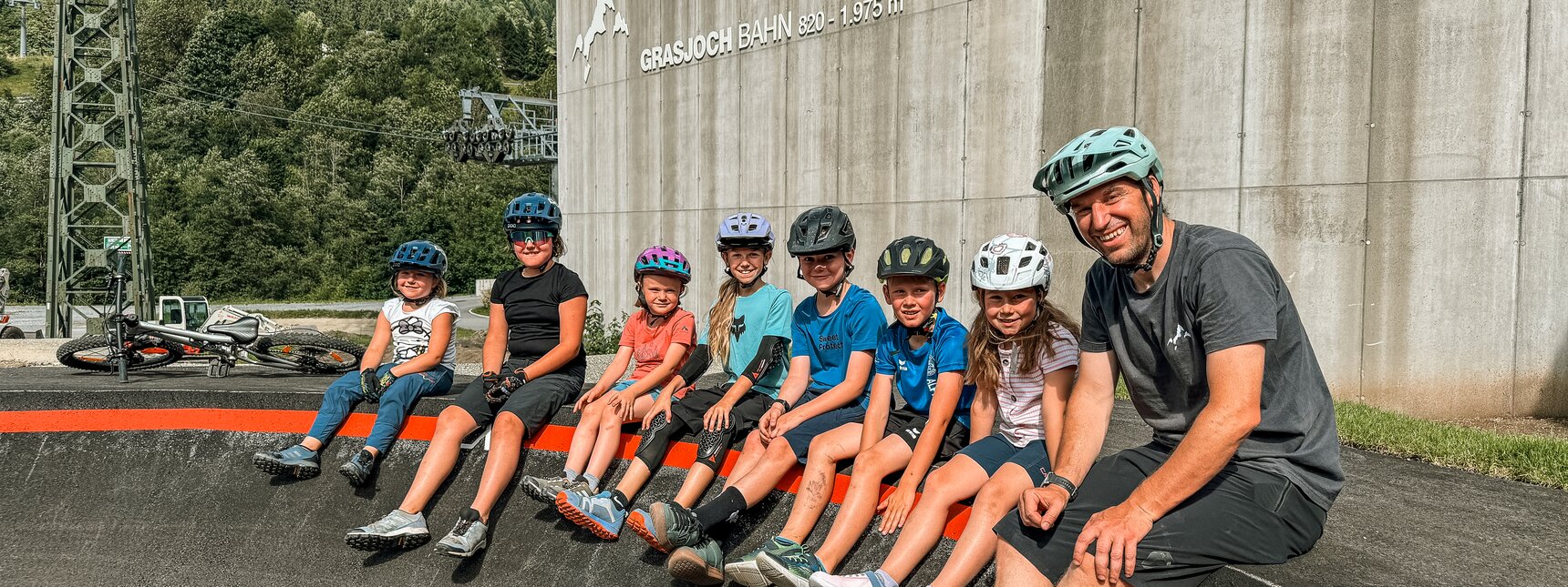 Eine Gruppe von Kindern mit Betreuer sitzen auf dem Rand des Pumptracks in der Silvretta Montafon. | © Vanessa Strauch - Silvretta Montafon
