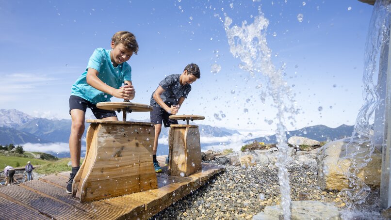 Vier Kinder an Wasserfontänen am Naturkräftepfad am Erlebnisberg Hochjoch in der Silvretta Montafon. | © Silvretta Montafon - Stefan Kothner