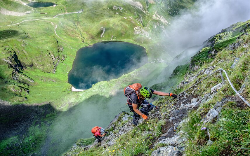 Zwei Personen im Klettersteig oberhalb eines Bergsees in der Silvretta Montafon. | © Silvretta Montafon - Bertram Waldner
