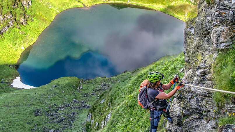 Eine Frau im Klettersteig oberhalb eines Bergsees in der Silvretta Montafon. | © Silvretta Montafon - Bertram Waldner